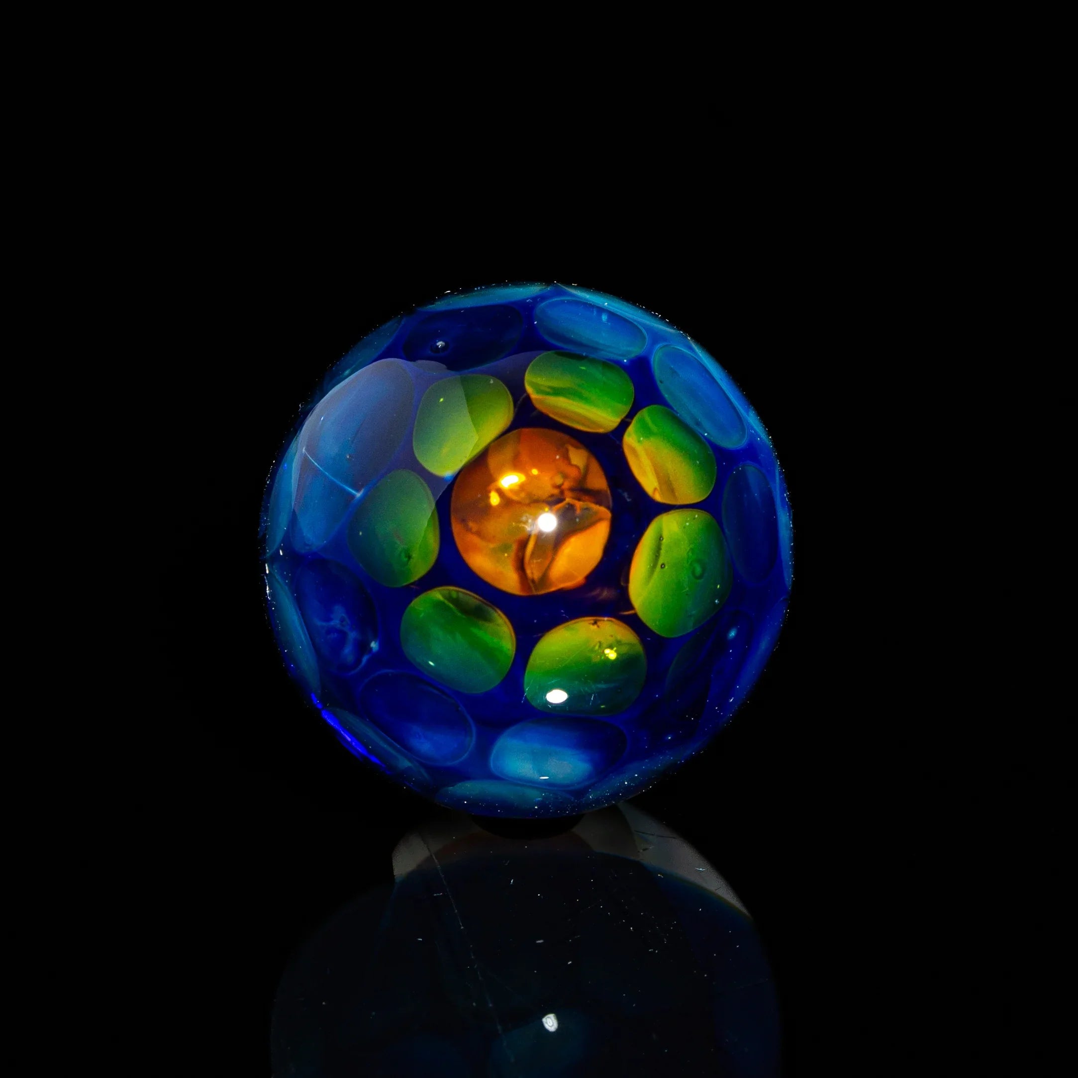 Colorful glass marble with blue, green, and orange details on a black background