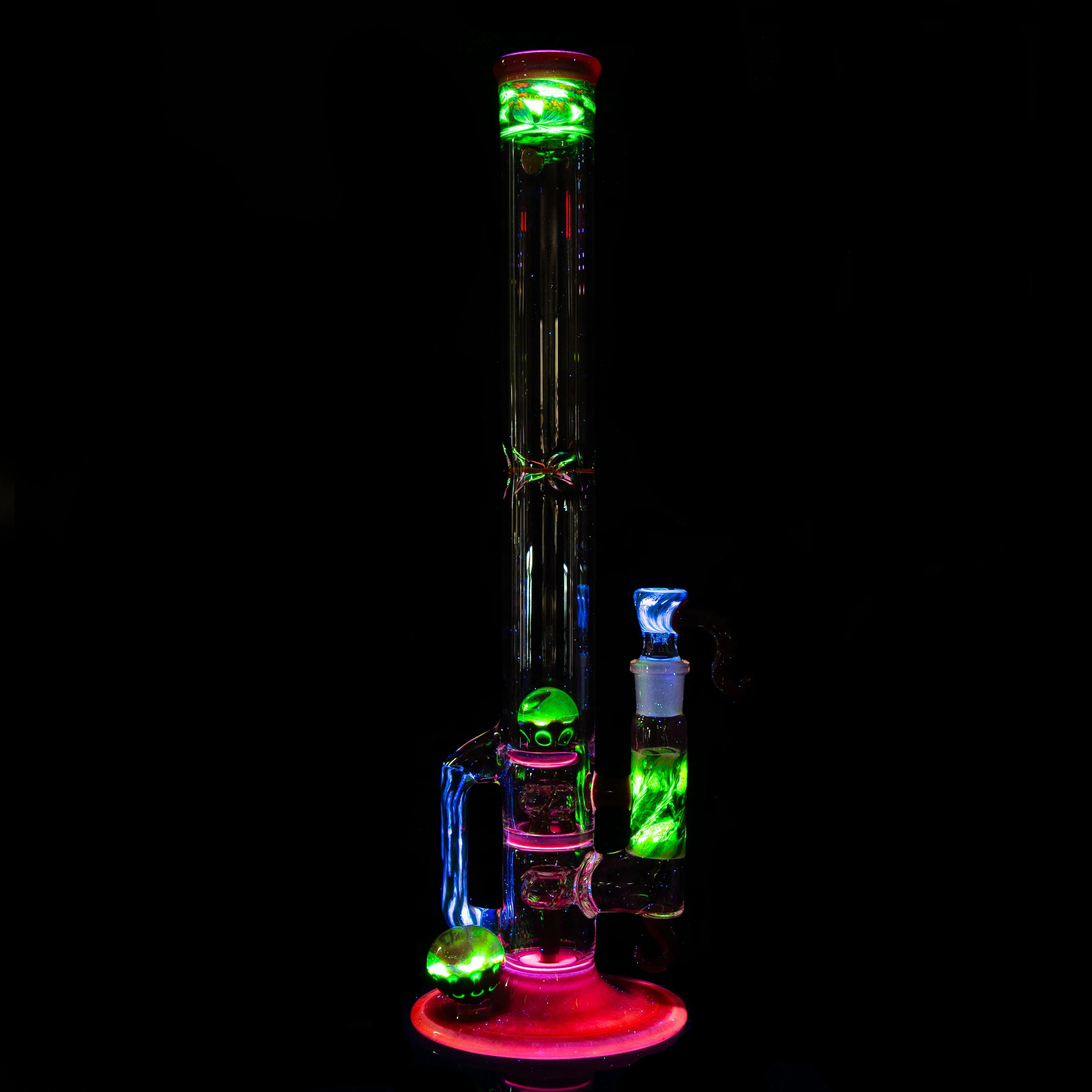 UV-reactive glass water pipe with glowing green and pink accents on black background