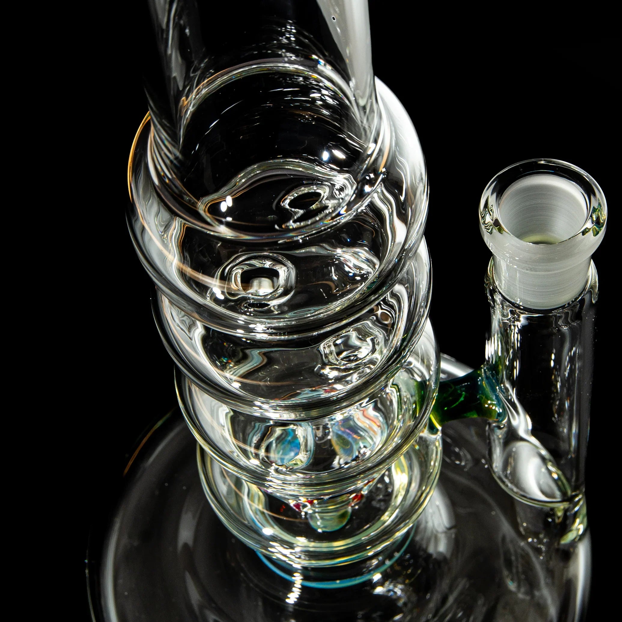 Close-up of a clear glass water pipe with spiral design on a black background