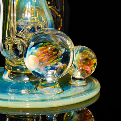 Heady glass art marbles with colorful fumed design on glass water pipe base, black background