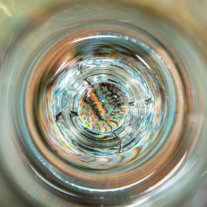 Intricate glass art marble with colorful patterns inside a clear glass pipe, macro view.