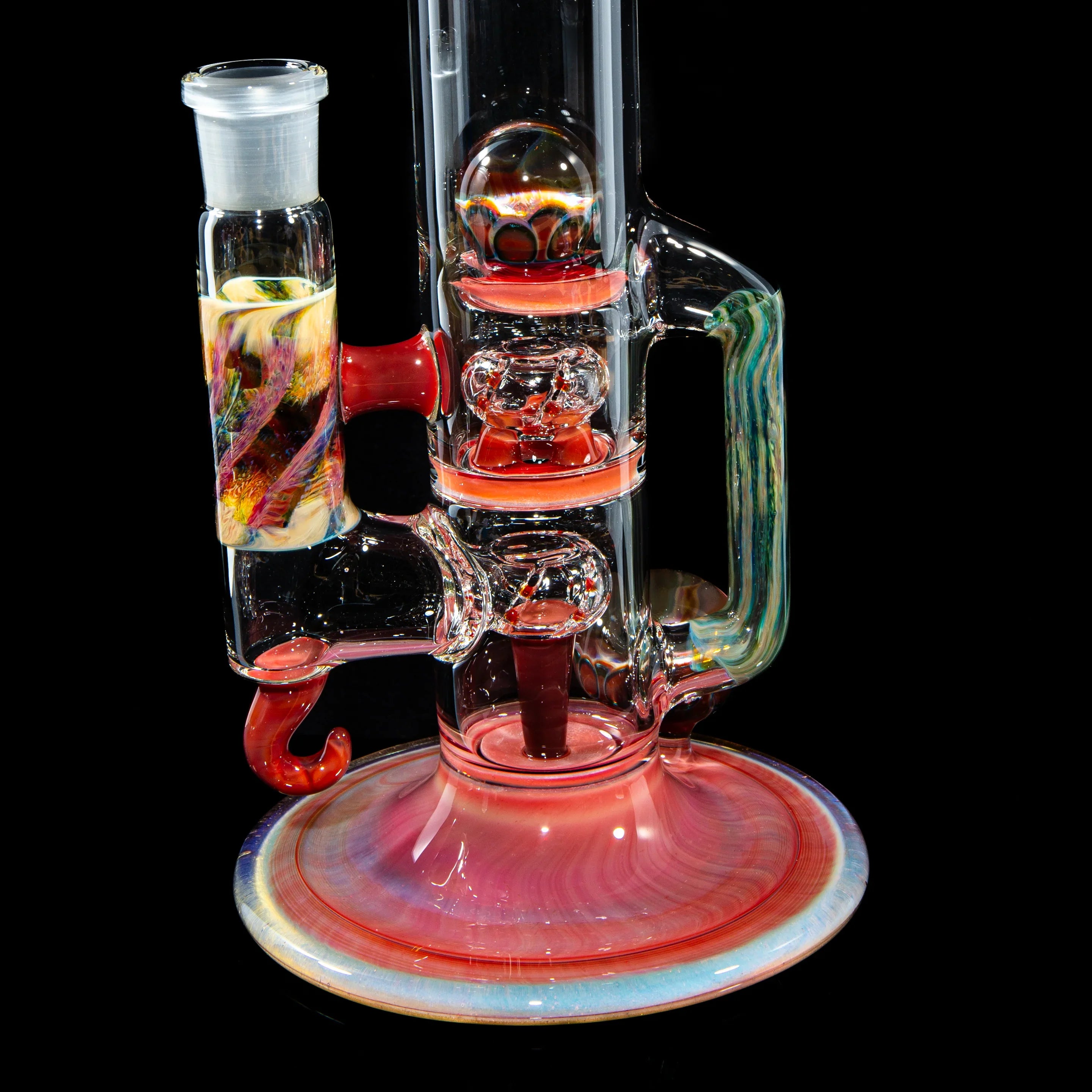 Colorful heady glass water pipe with intricate designs and handle on black background