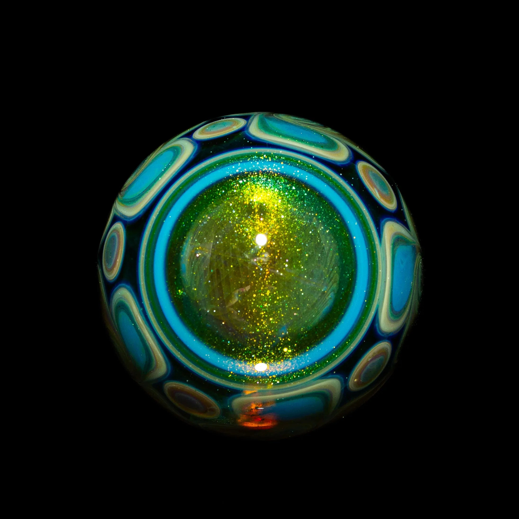 Handcrafted glass art marble with sparkling green center and blue patterned swirl design