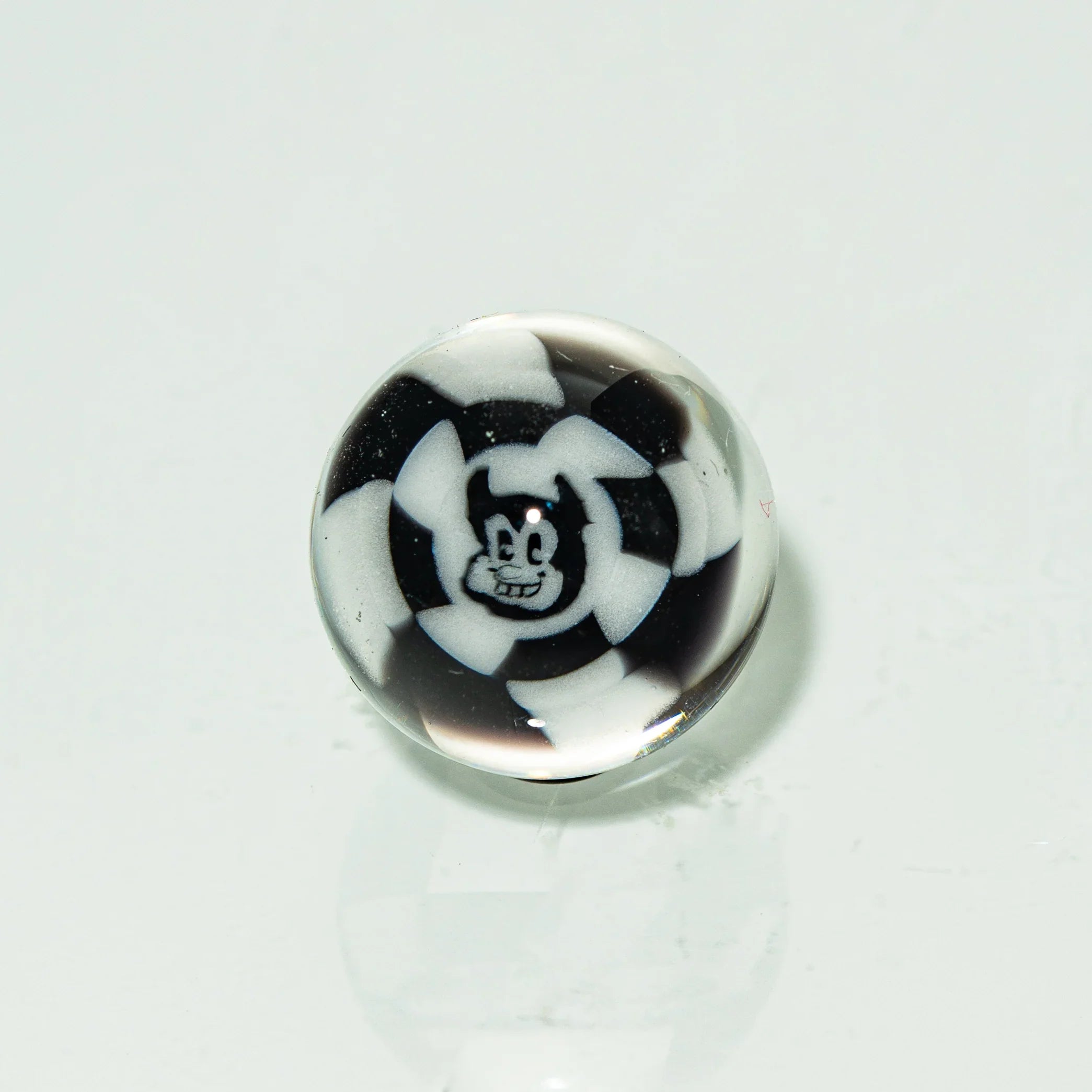 Black and white glass marble featuring a cartoon face design on a white background.