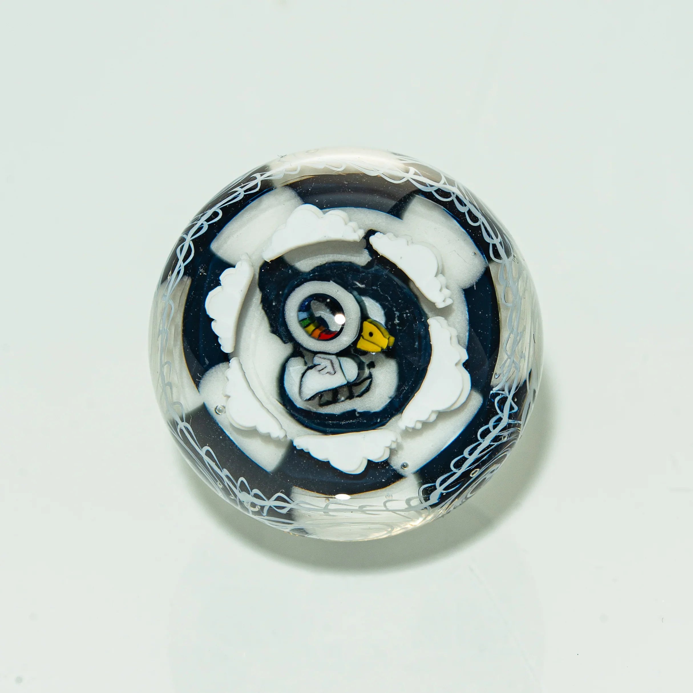 Art glass marble with penguin design and intricate white patterns on clear background