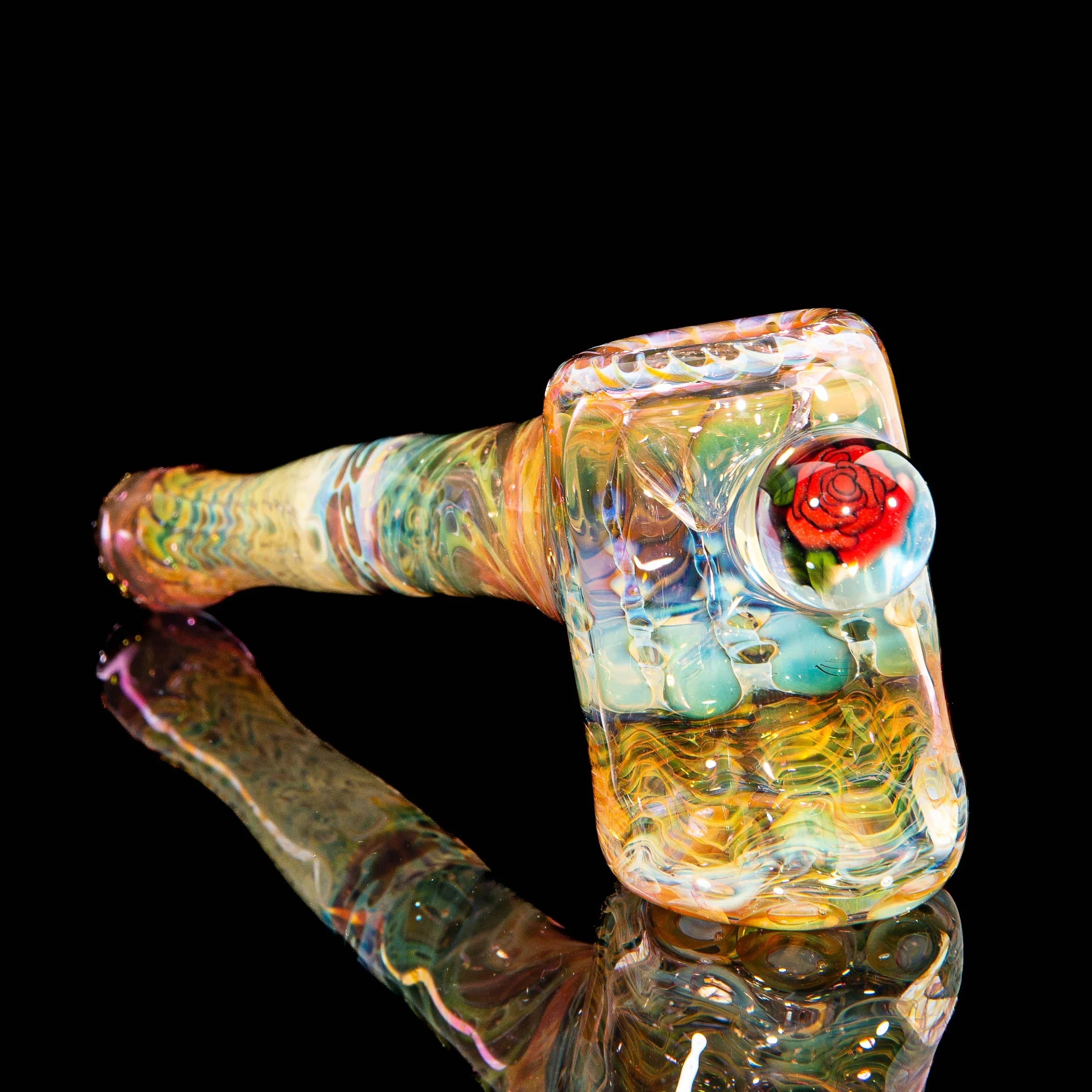 Colorful heady glass hammer pipe with intricate patterns and a red flower detail on black background