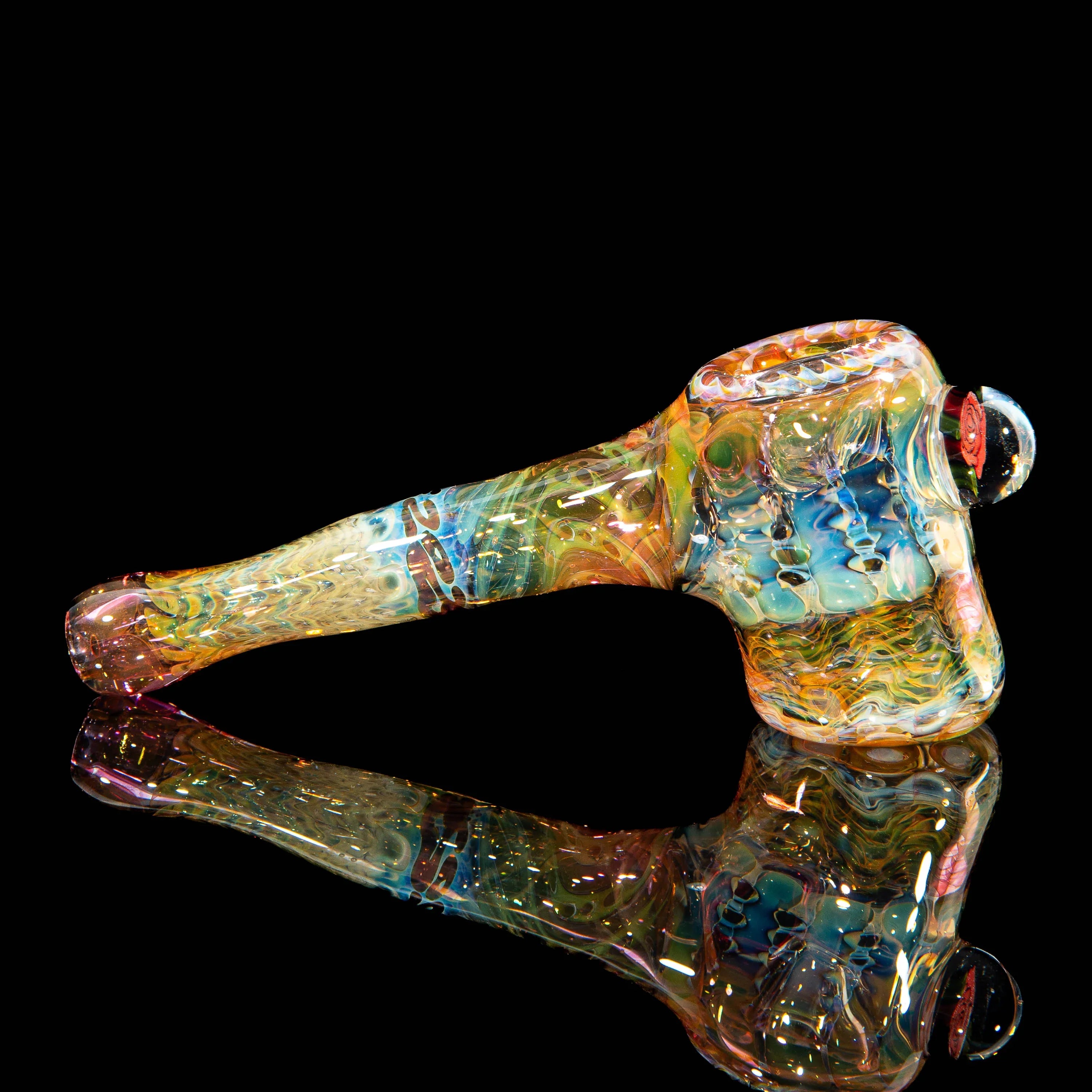 Colorful hand-blown glass pipe with intricate patterns on a black reflective surface