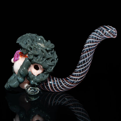 Hand-blown glass pipe with detailed sculpted face and spiral patterned stem on black background