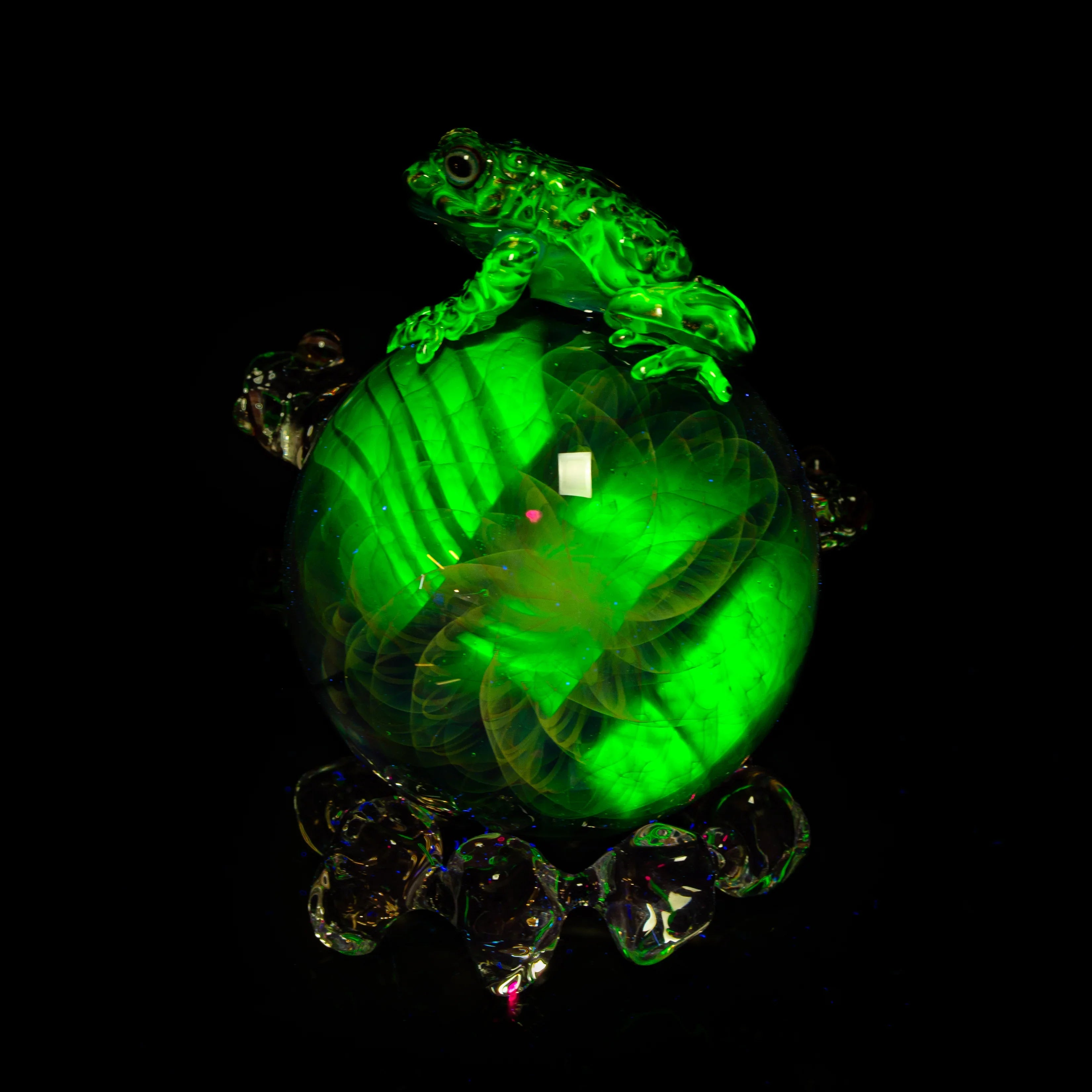 Heady glass art marble with green frog sculpture, luminous details on black background