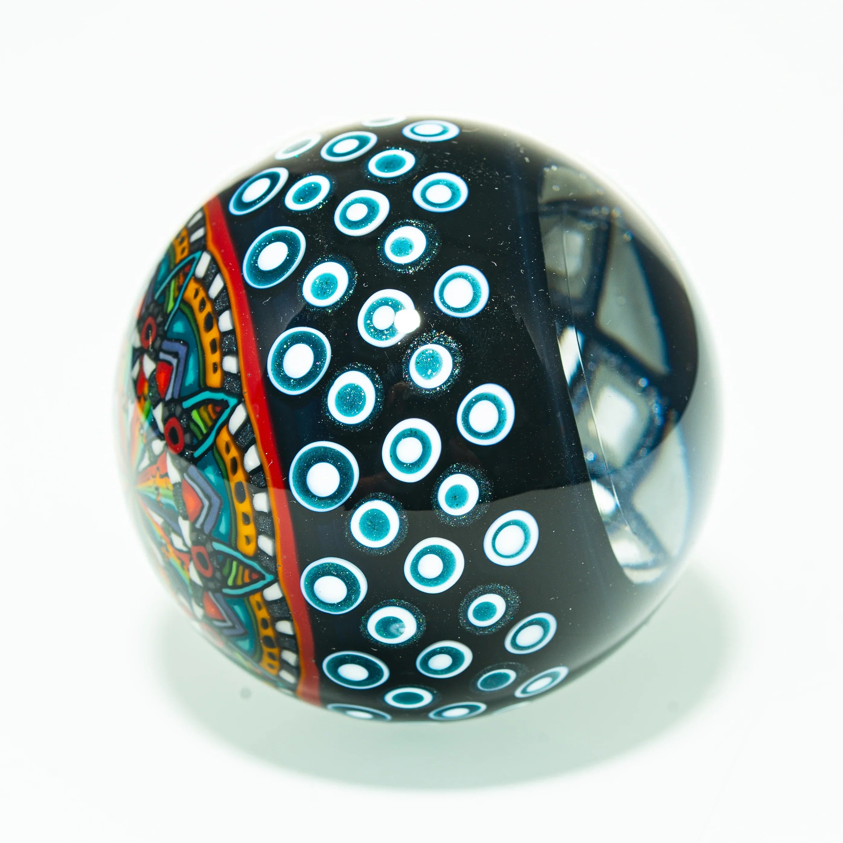Colorful heady glass marble with geometric patterns and blue dot accents on white background