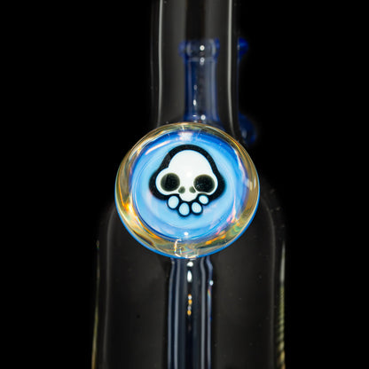 Close-up of glass water pipe with blue accent and skull design medallion
