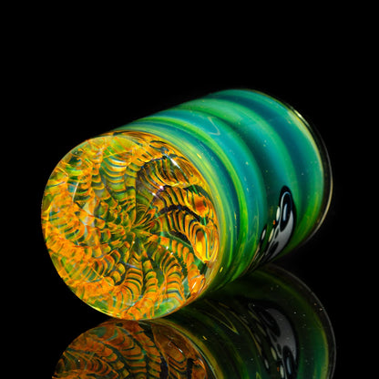 Colorful hand-blown glass cup with green, yellow, and orange spiral pattern on black background