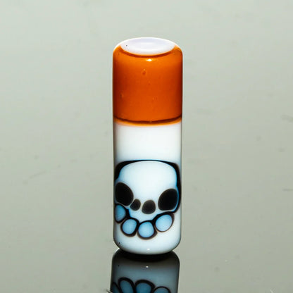 Hand-blown glass accessory with orange top and skull design on white background