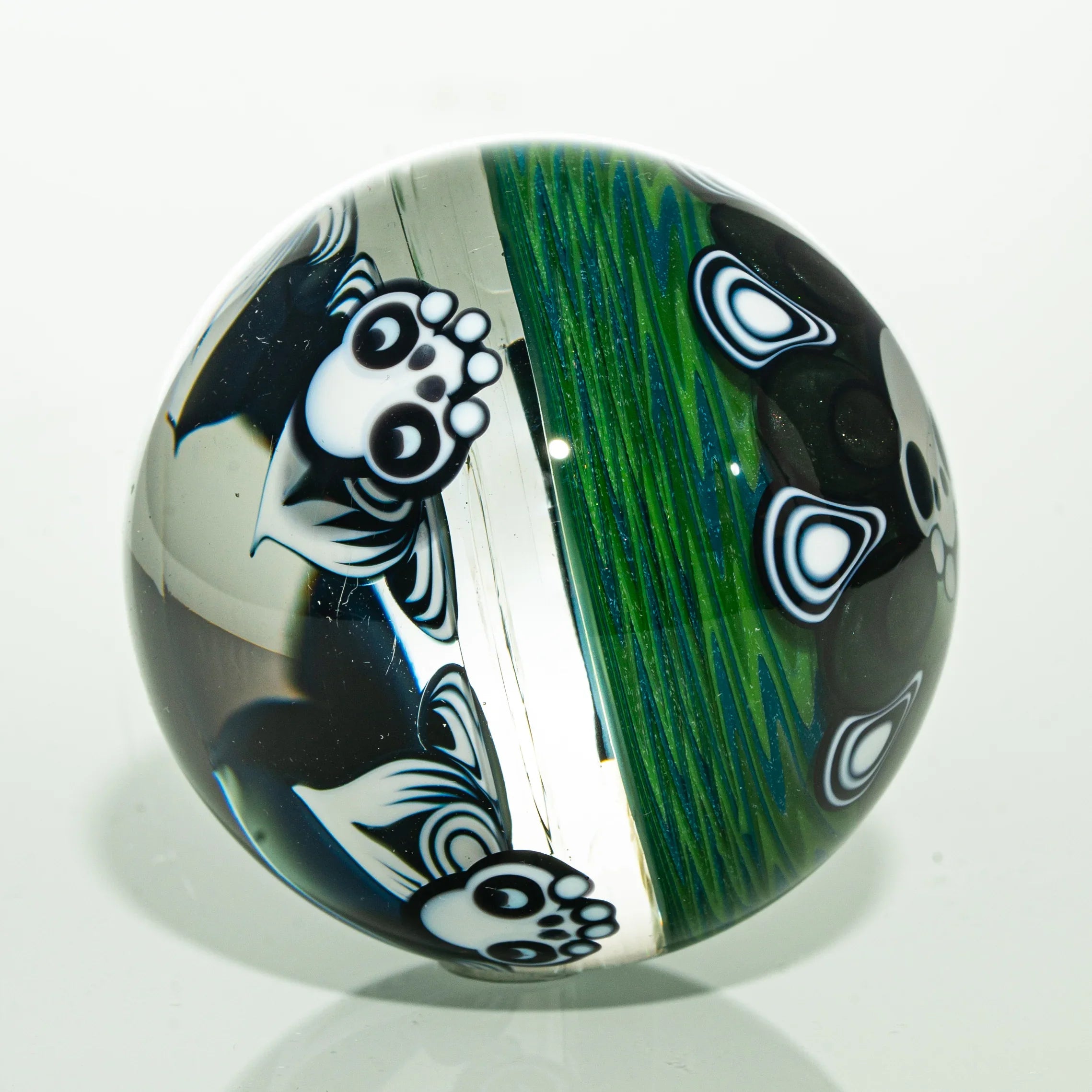 Handmade glass marble featuring panda designs and vibrant green linework on clear background