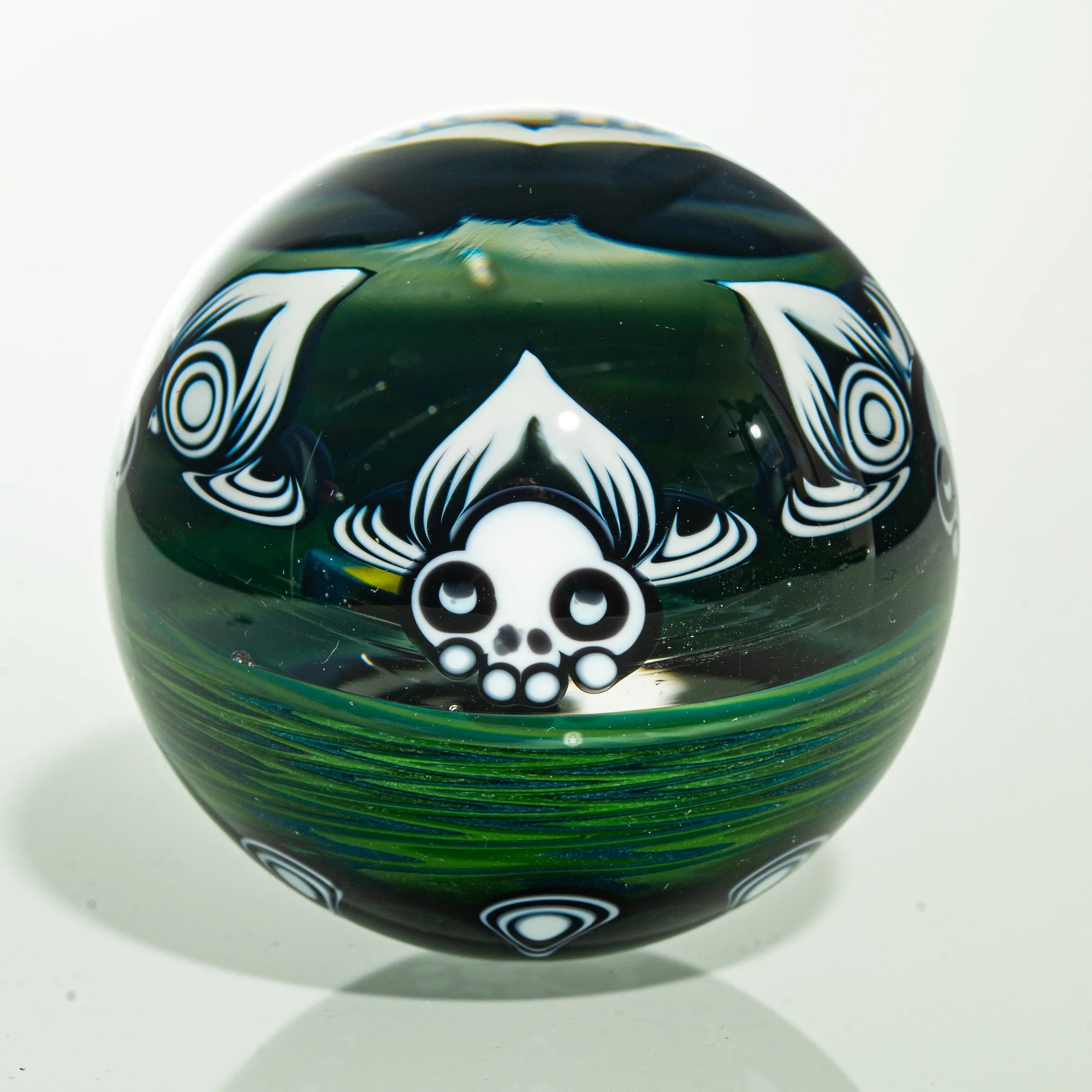 Handcrafted glass marble with intricate skull and leaf designs, heady glass art