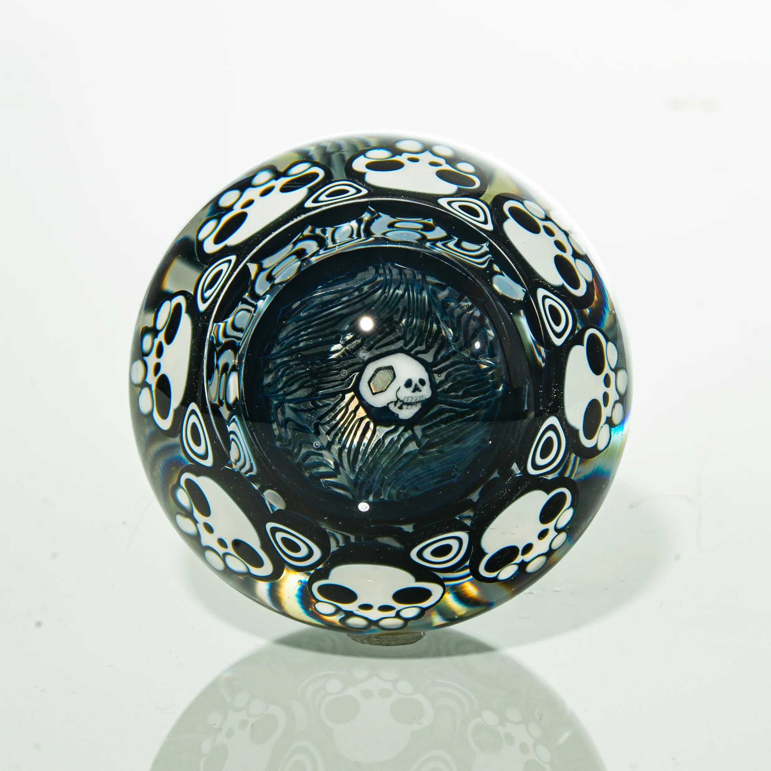 Glass marble with white skull and paw print designs on a clear background