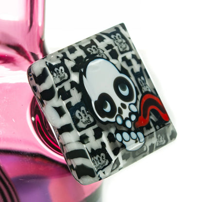 Close-up of pink glass bong with black and white skull art and cartoon face details