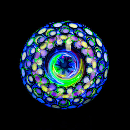 Colorful heady glass art marble with intricate UV reactive patterns on a black background