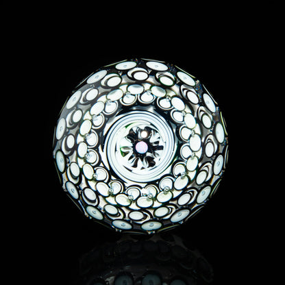 Handcrafted glass marble with intricate white and black swirling patterns on black background