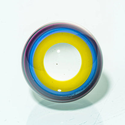 Colorful glass marble with yellow, blue, and purple rings on a white background