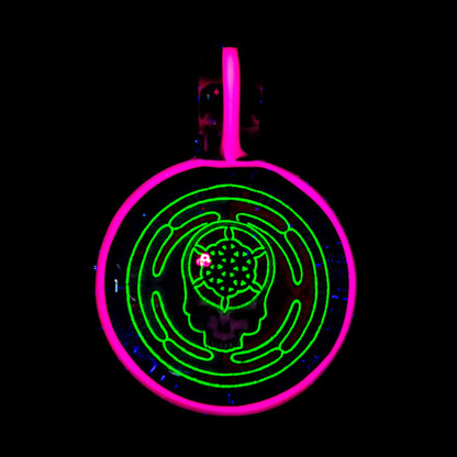 UV-reactive glass pendant with neon pink and green skull labyrinth design on black background
