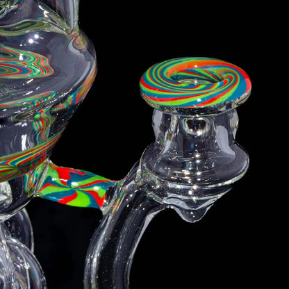Close-up of a clear glass dab rig with colorful swirl accents on a black background