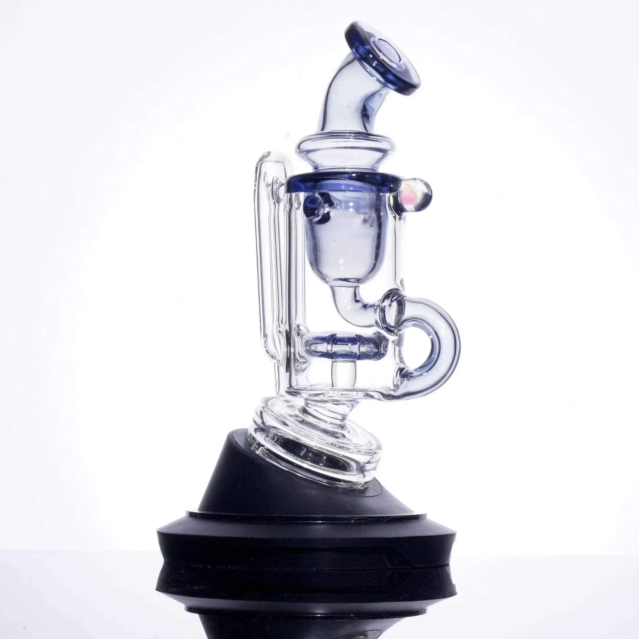 Clear glass rig with blue accents and percolator, displayed on black stand for heady glass collection