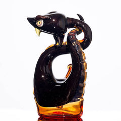 product shot of glass snake made by Niko Cray in Pomegranate over steel wool and tangjello
