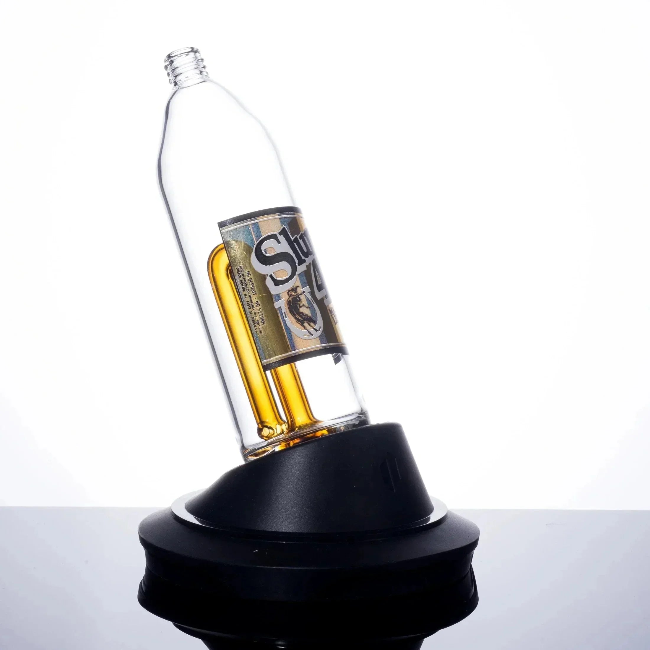 Clear glass bottle bong with amber chamber and branded label, displayed on black base