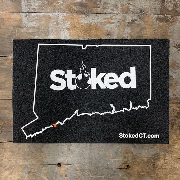 Stoked 12x18 inch mood mat, state of connecuticut outline with orange star, stoked logo centered. Stoked URL bottom right.