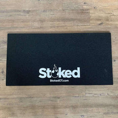 17x34 inch black moodmat on wood background, with Stoked logo centered bottom
