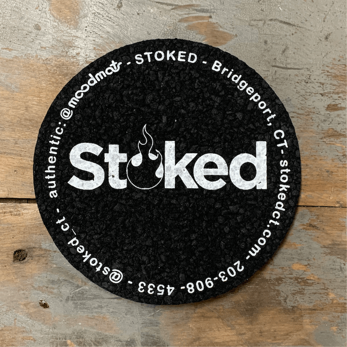 Stoked 5 inch coaster mood mat, black circular mat with Stoked logo in the center; written along circular edge is Stoked, Bridgeport CT, stokedct.com, 203-908-4533, @stoked_ct, @moodmats