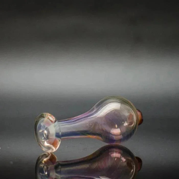 Iridescent glass bubble cap for dab rig on reflective black surface