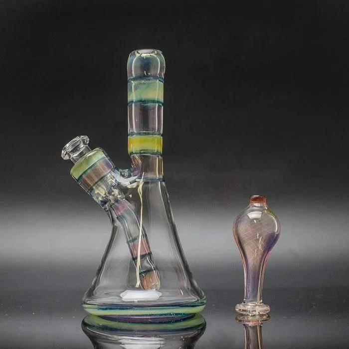 Removable downstem glass rig with matching bubble cap, iridescent striped design on dark background.