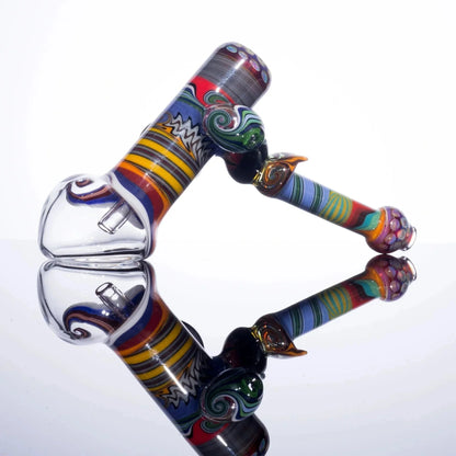 Colorful glass bubbler pipe with intricate swirl patterns reflected on a white surface