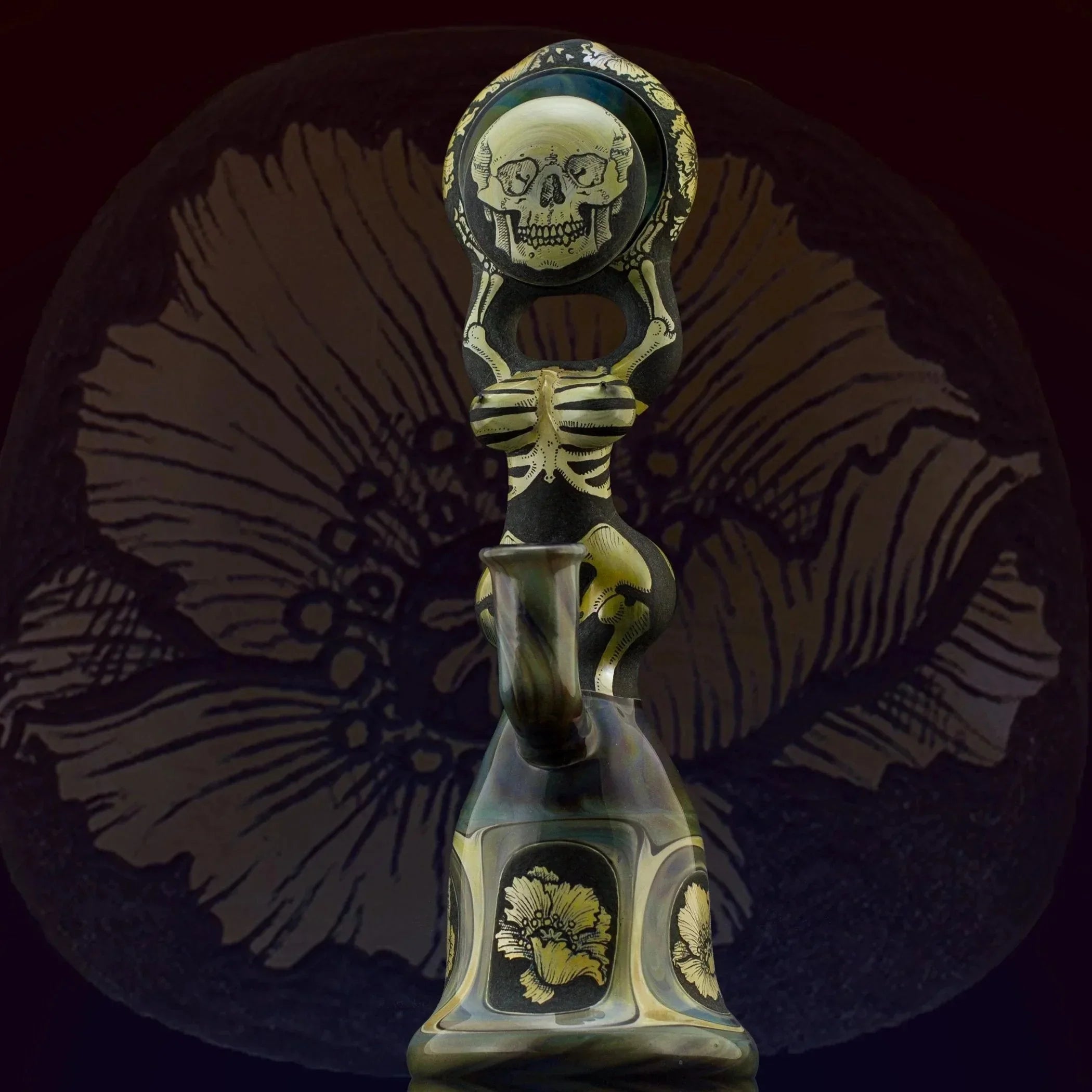 Intricate glass water pipe with skeleton and skull motif, gold floral accents, and dark tones.