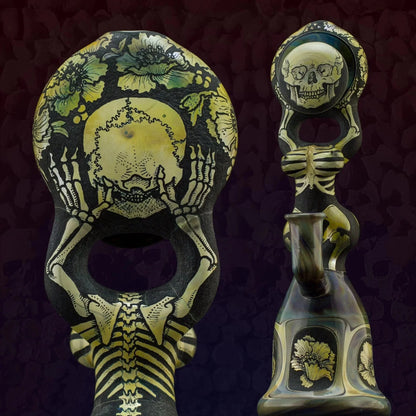 Intricately detailed glass water pipe with skeleton and floral designs on dark background