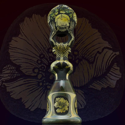 Artistic glass pipe featuring intricate skeleton and floral designs on a dark background