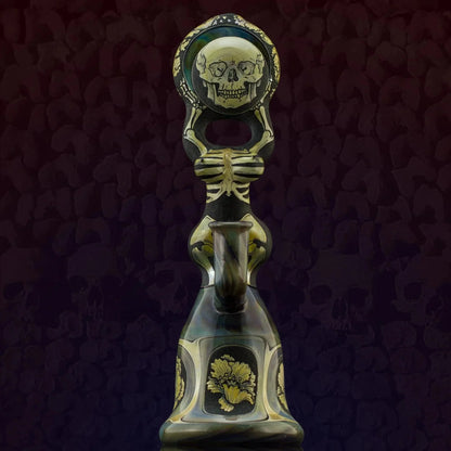 Intricately designed glass water pipe featuring a skeleton and skull art with gold accents