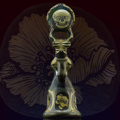 Intricately designed glass water pipe with gold skull and flower motifs, front view