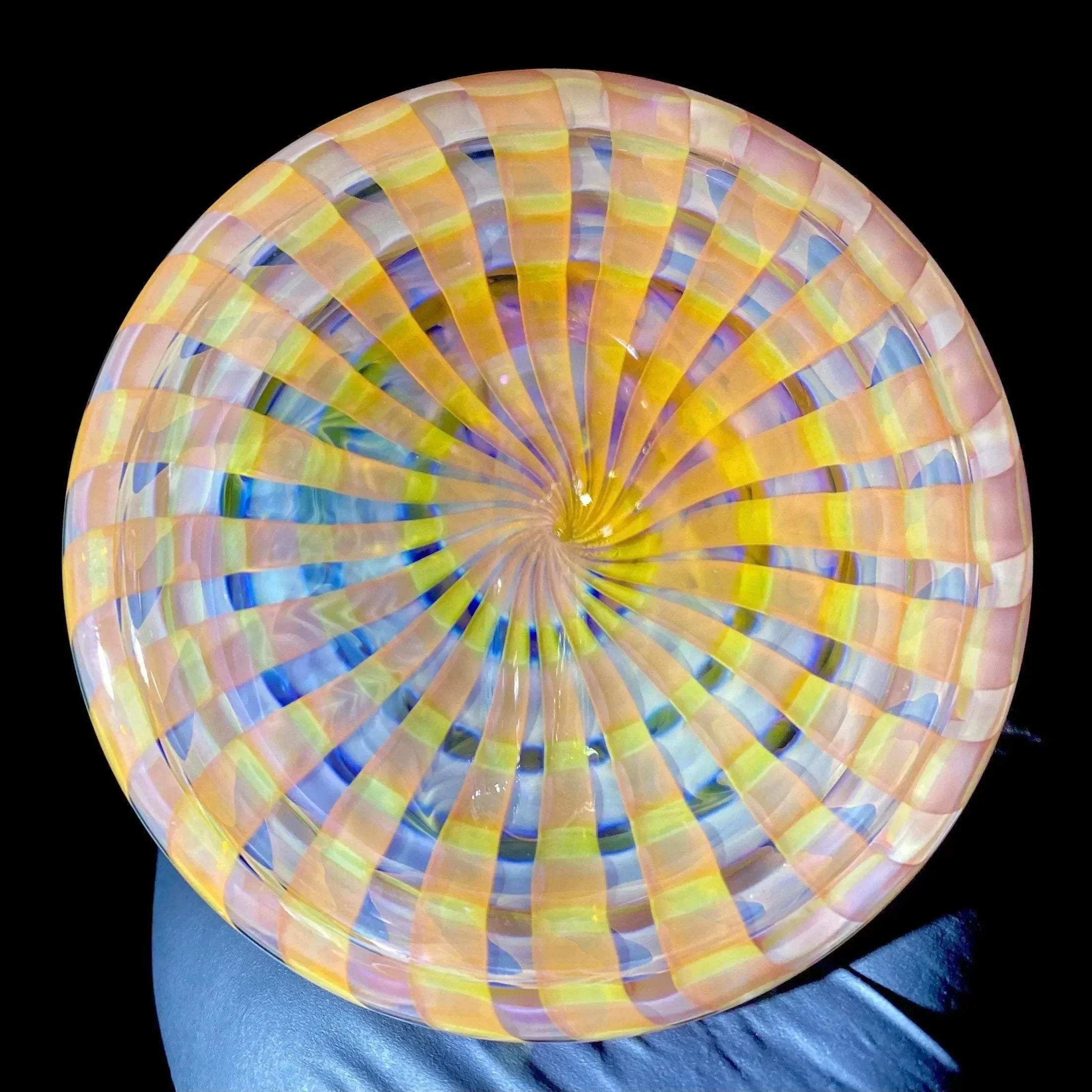 Colorful hand-blown glass bowl with spiral lattice pattern, viewed from above